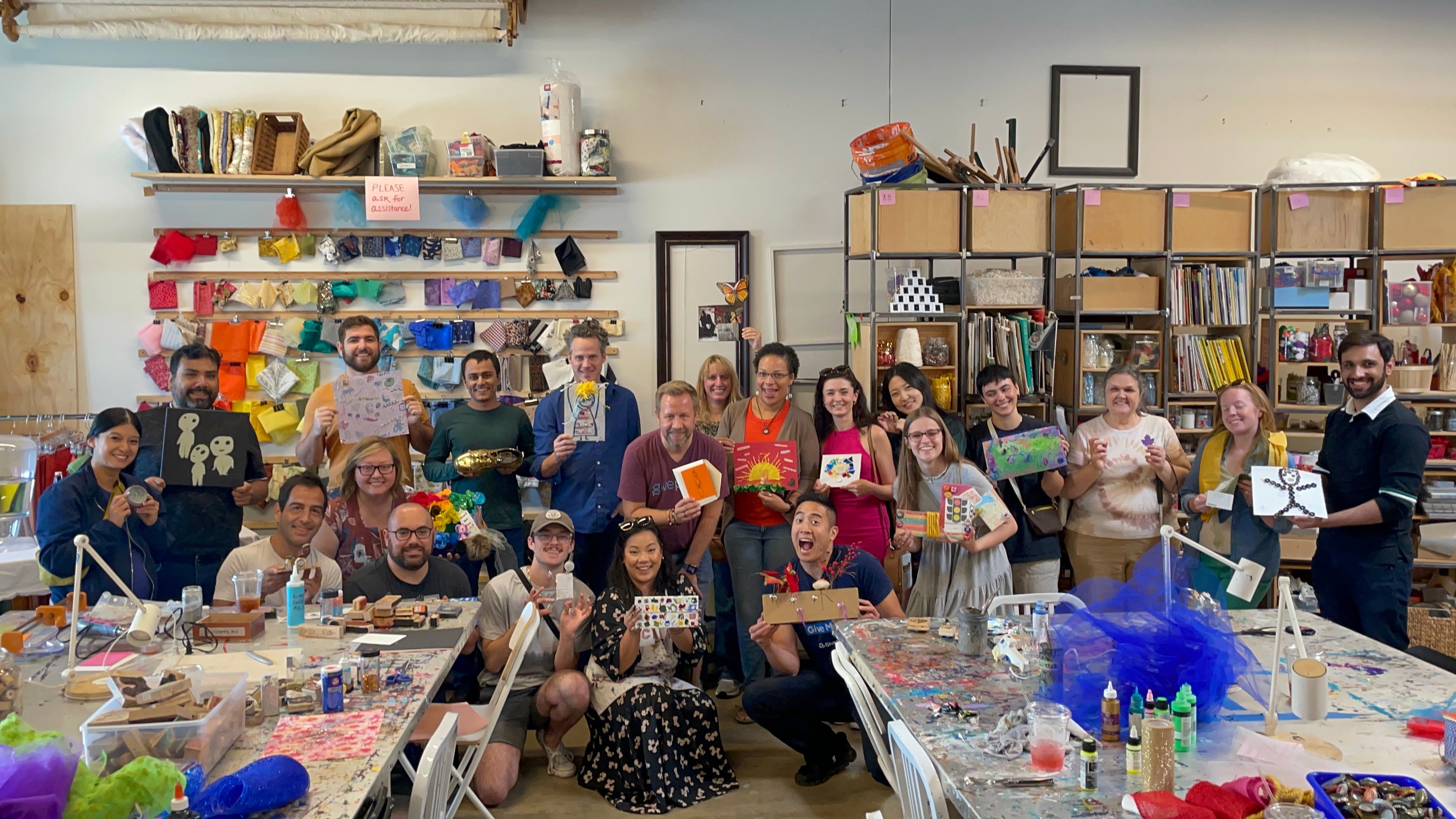GivePulse team members smiling while on the '22 company retreat. The GivePulse team is holding up pieces of art they made while in Austin Texas.