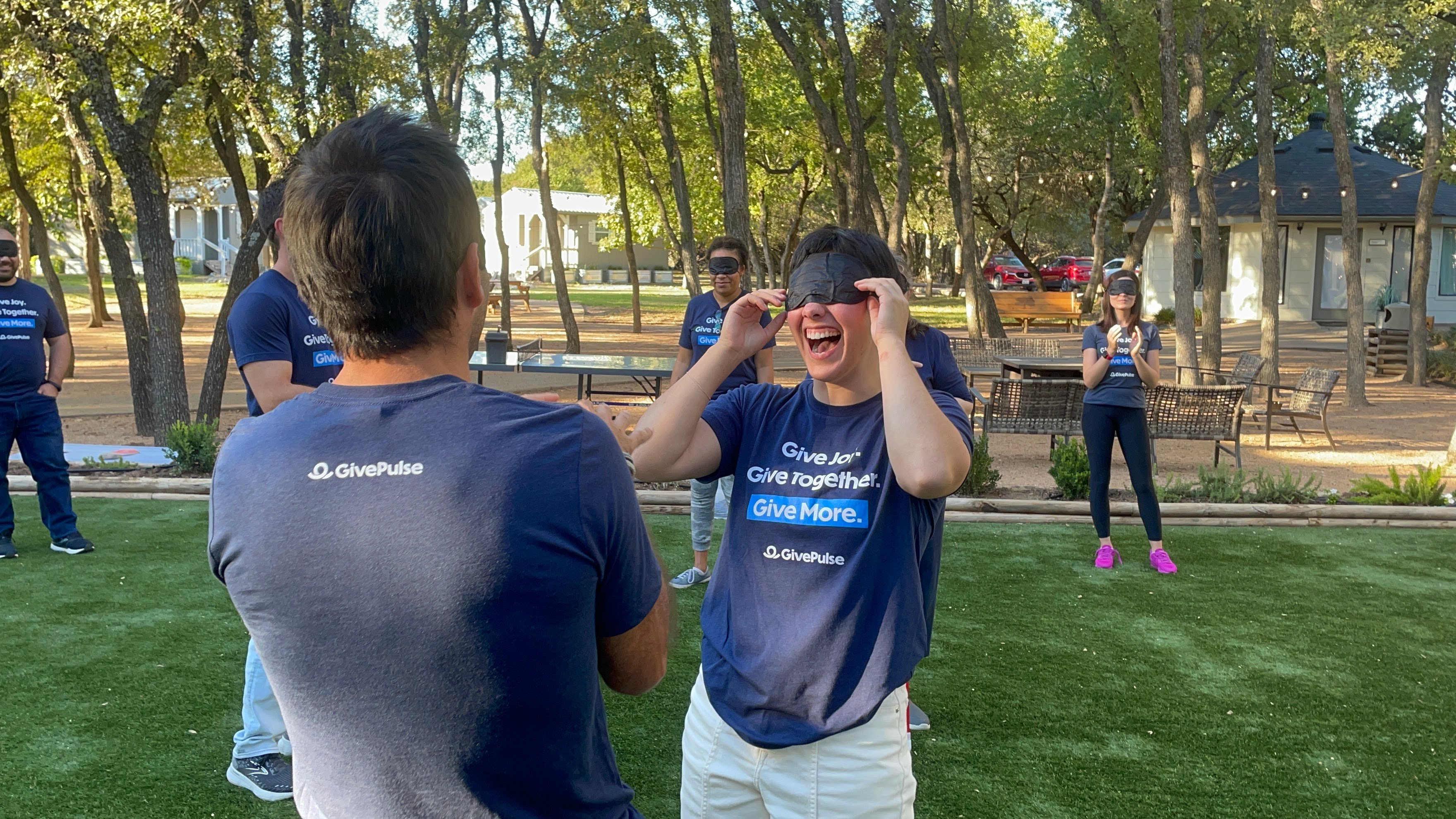 GivePulse team members smiling with blindfolds on playing a team building game
