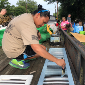 GivePulse volunteer painting a shutter for a window