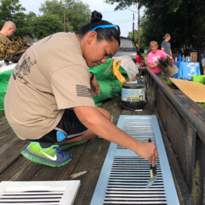 GivePulse volunteer painting a shutter for a window 