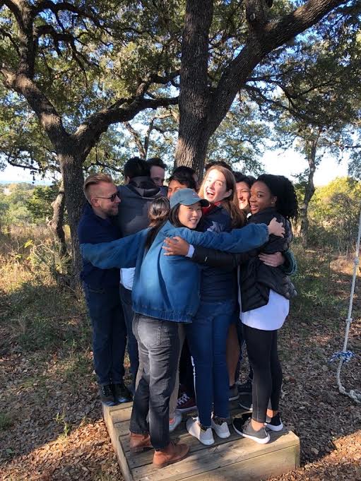 GivePulse team members engaging in team-building exercises, standing on a small wooden platform