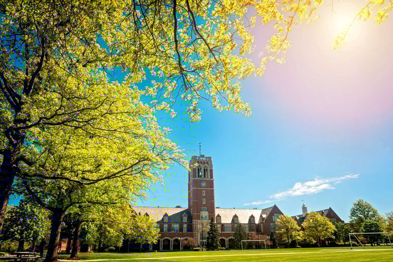 Campus building at John Carroll University in the spring or summer with trees blooming in the foreground 