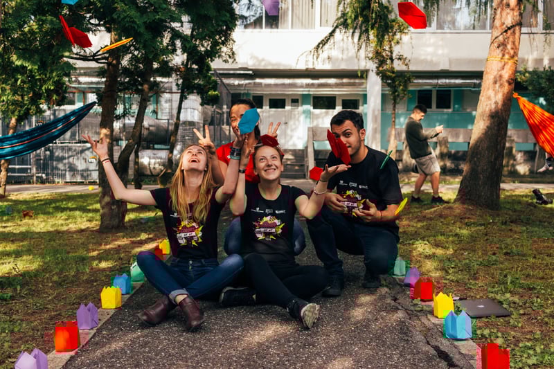 Three student volunteers sitting in their university quad smiling and laughing 