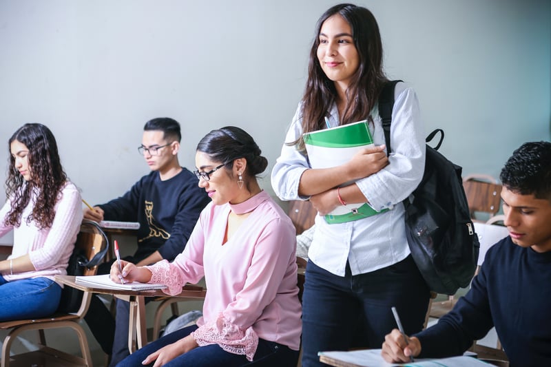 Student walking into a university or college class on service learning holding books 