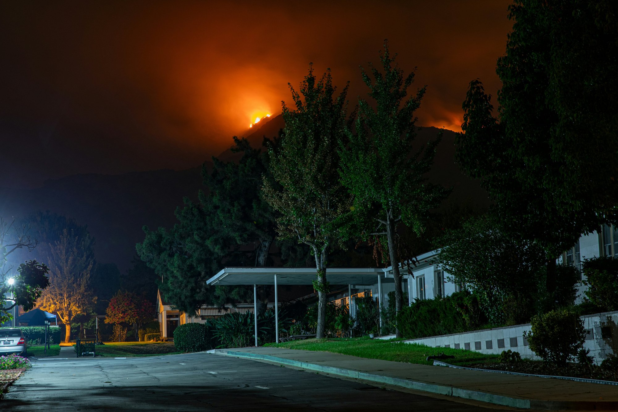 Wildfires peaking over a mountain above neighborhood in California