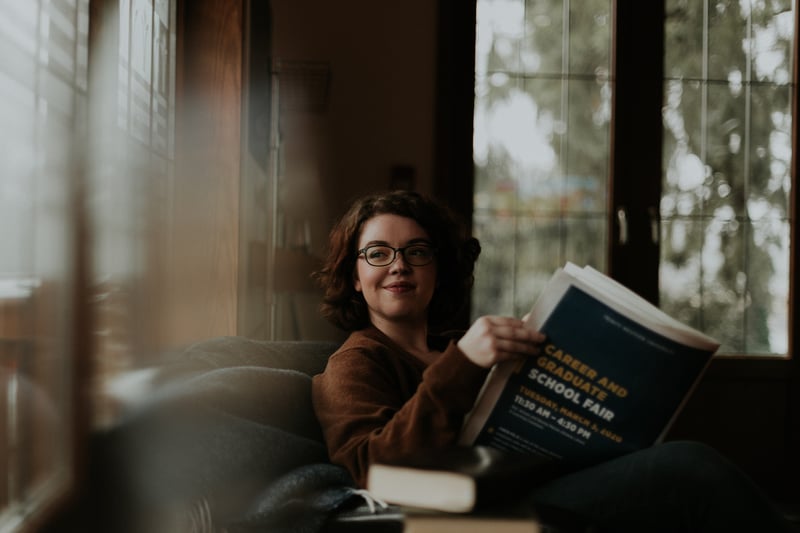 Student volunteer smiling while reading a book