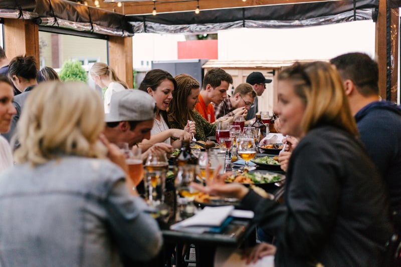 Group of individuals sitting at a table outside eating lunch at a fundraising event