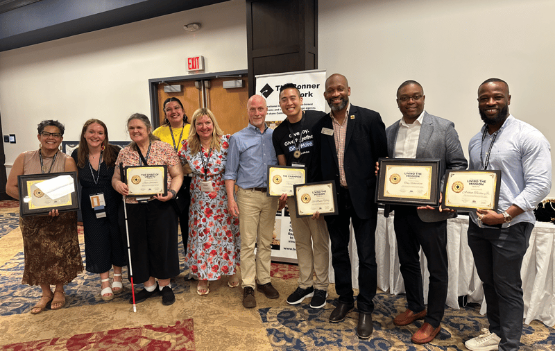 Group picture at the GivePulse booth with friends, clients, and partners at a higher education conference for community engagement