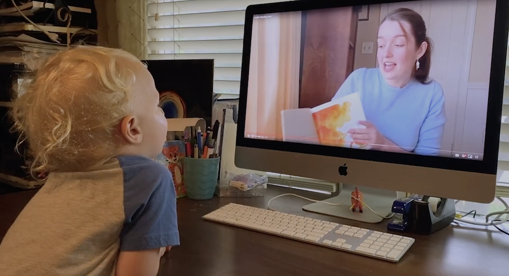 Virtual volunteer is reading a book and mentoring a child from afar through a real time webinar