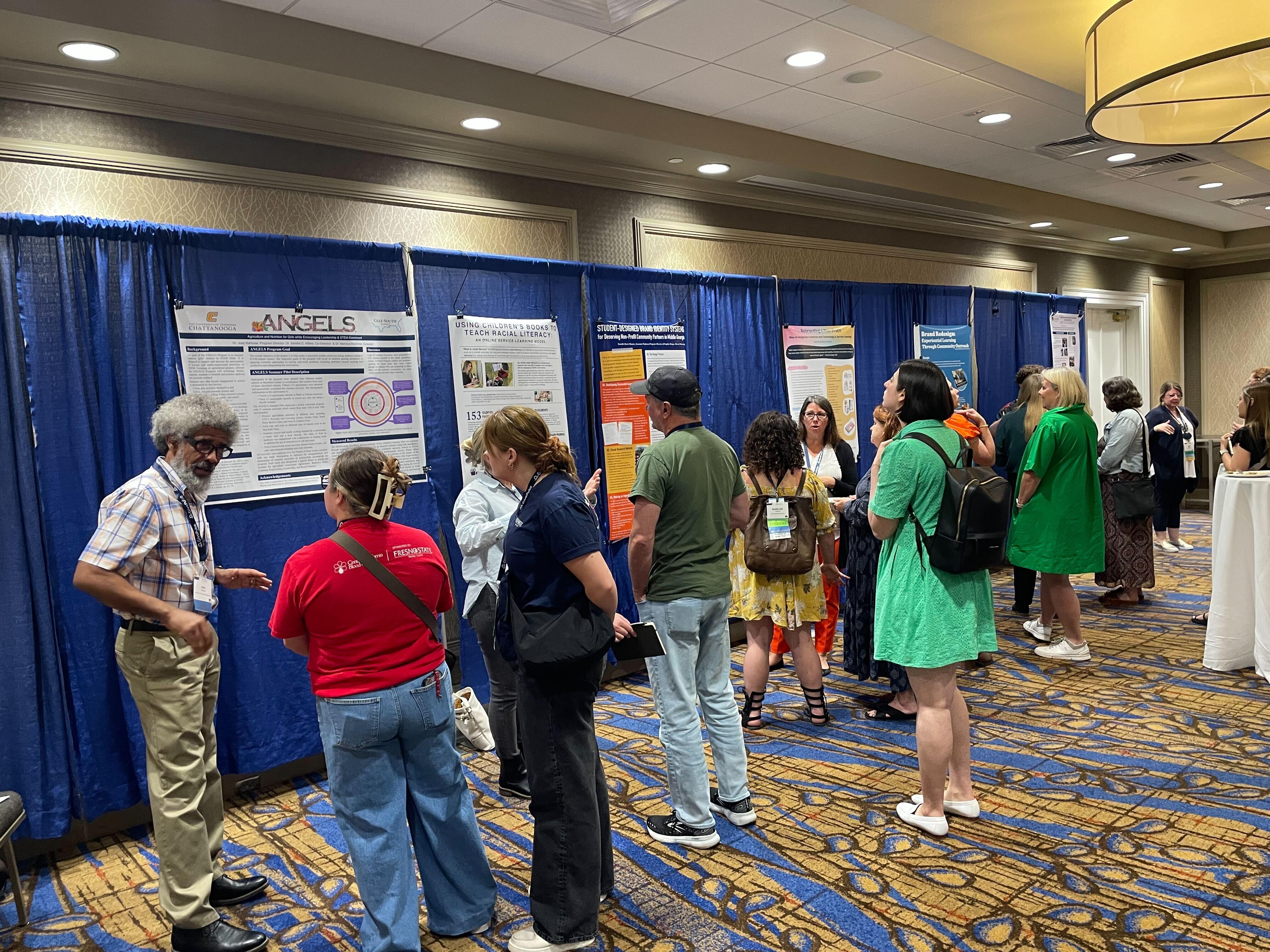 People walking around the exhibit hall at the Gulf South Summit conference looking at presentation posters