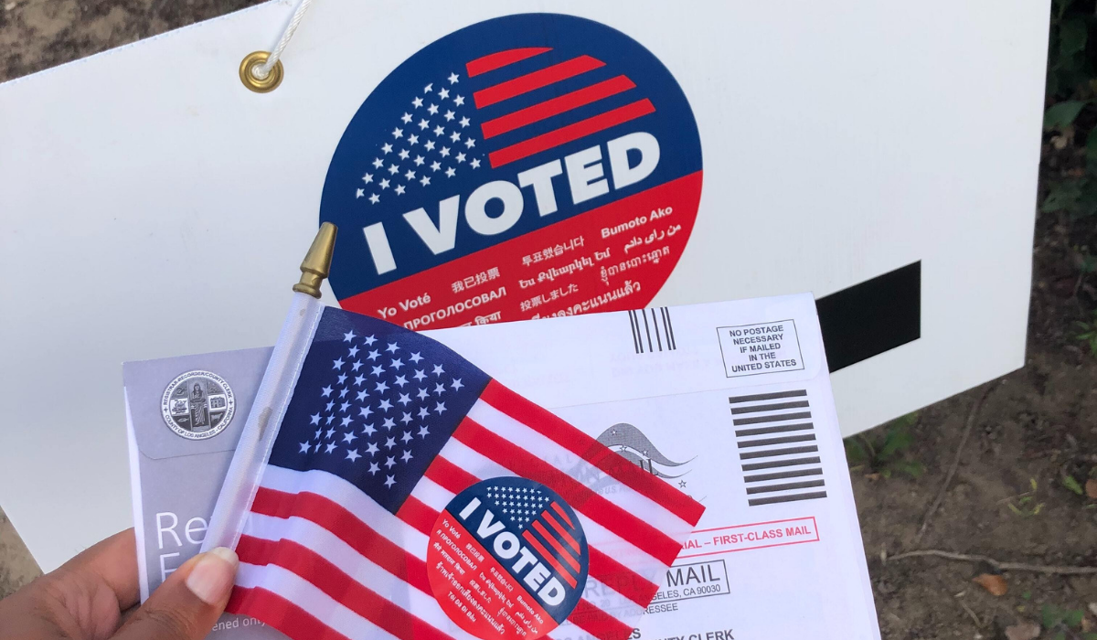 Background image of a person holding an "I Voted" sticker with text over reading: Best way to celebrate democracy? Strengthen it!