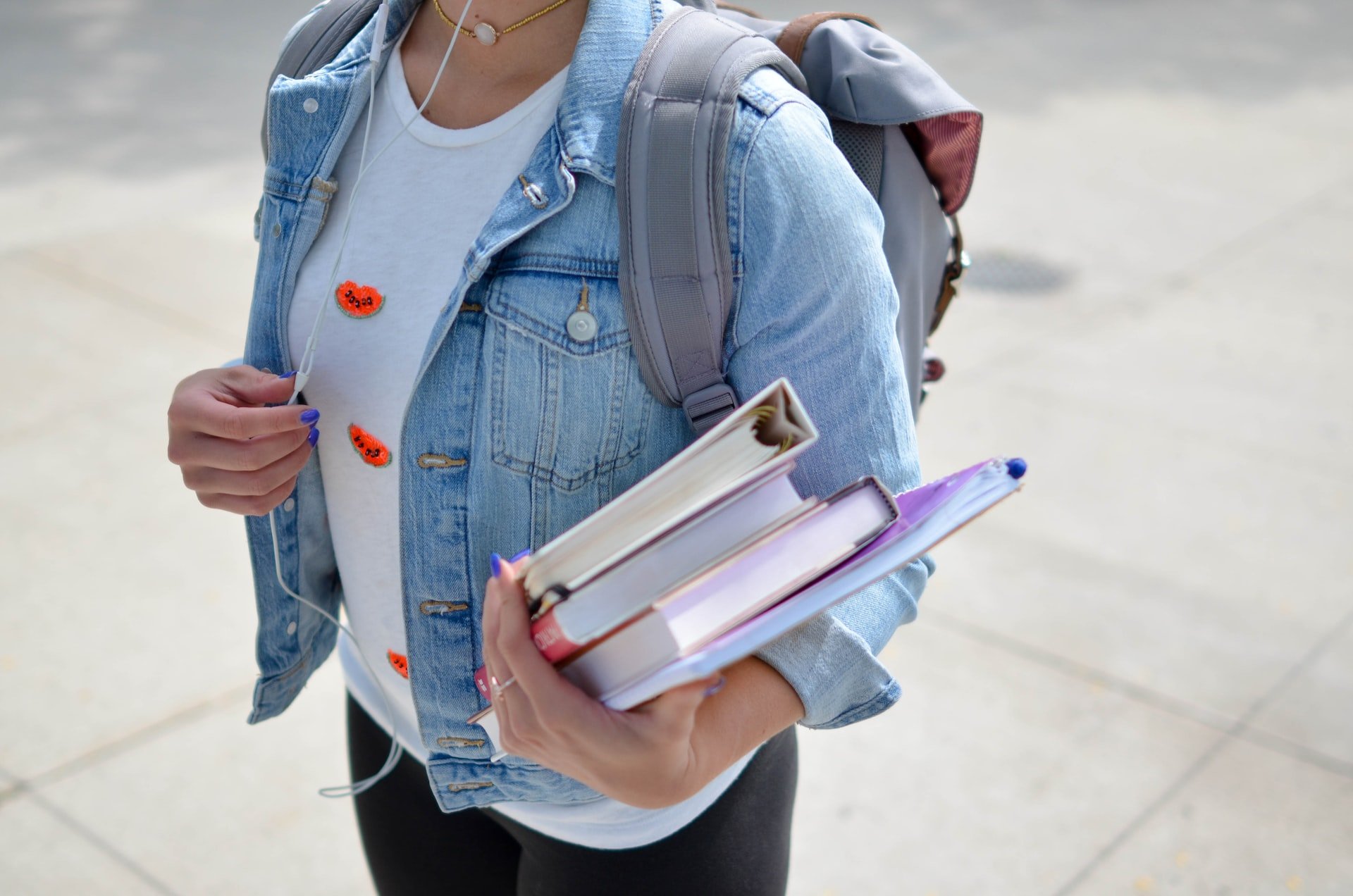 A student carrying textbooks and binders.