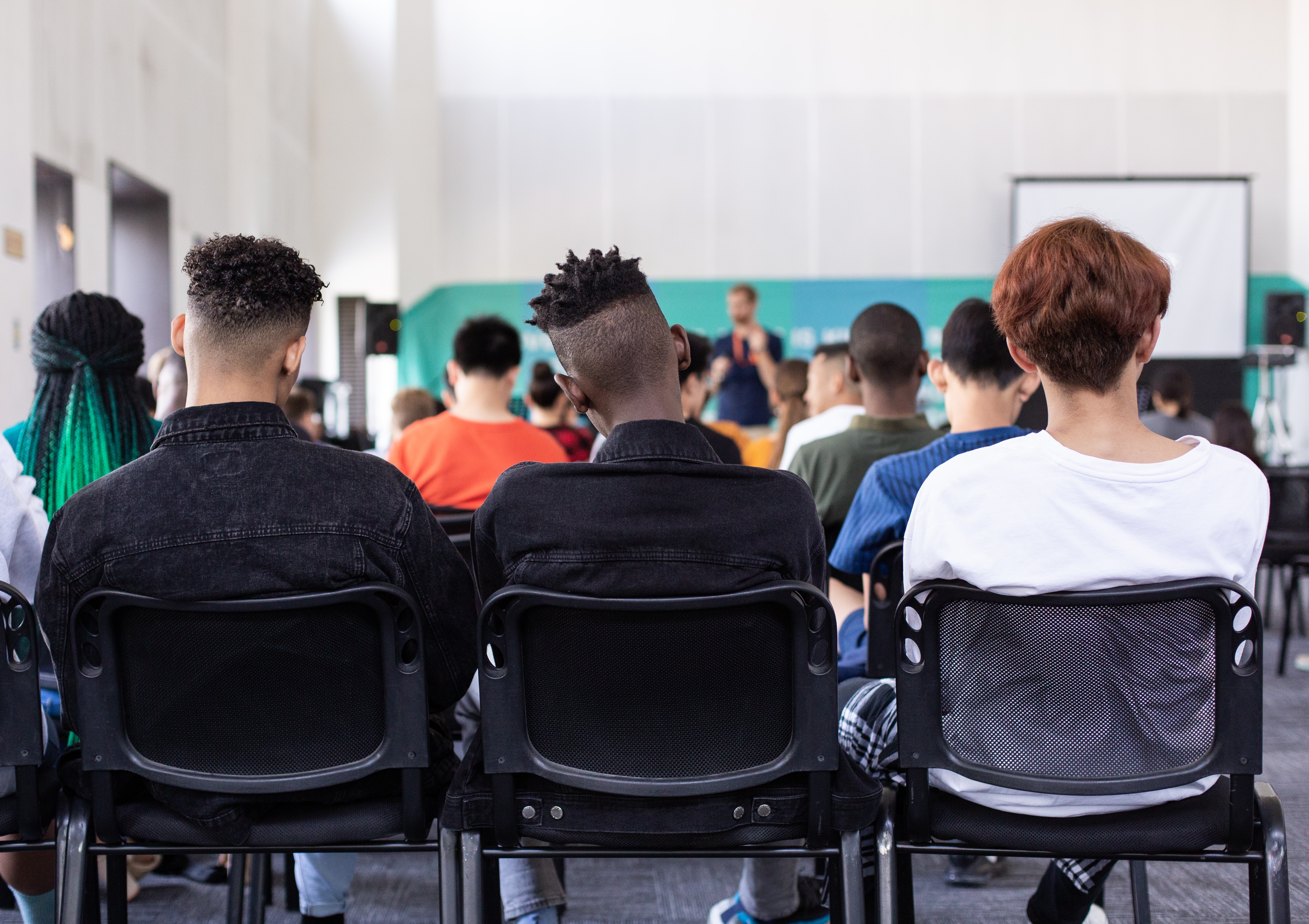 Students, faculty, and staff sitting in a conference room listening and engaging with a panel discussion